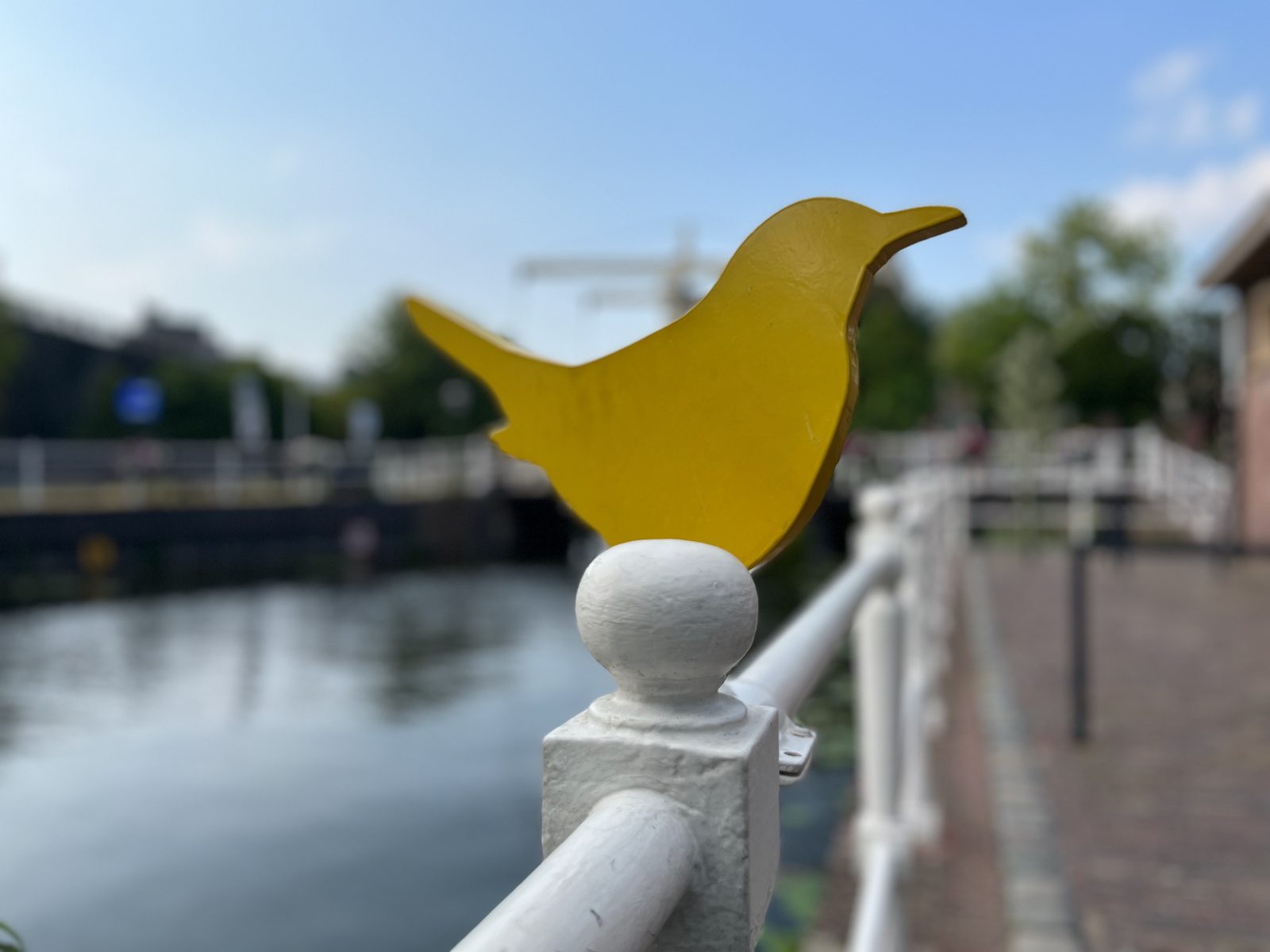 Yellow bird sculpture on a canal railing