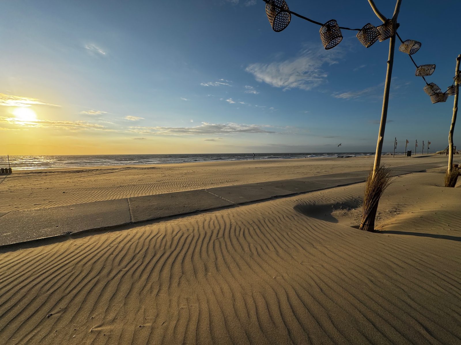 Beach at sunset with string lights and rippled sand